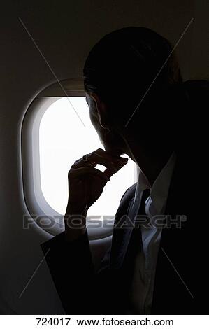 A female passenger looking through a window on a plane View Large Photo Image Stock Photo - A female passenger looking through a window on a plane. Fotosearch