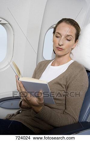 Picture - A female passenger reading on a plane. Fotosearch