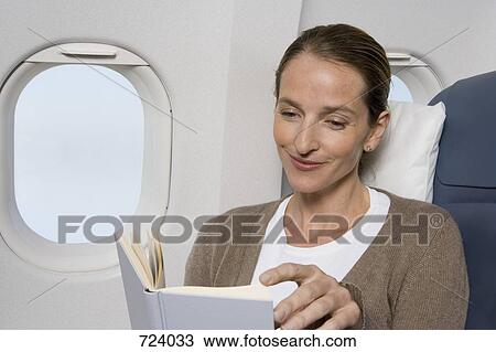 A female passenger reading on a plane View Large Photo Image Stock Image - A female passenger reading on a plane. Fotosearch