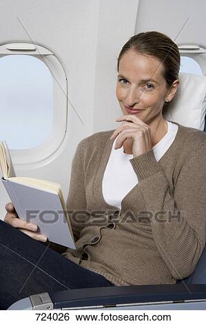 A female passenger reading on a plane View Large Photo Image Stock Photograph - A female passenger reading on a plane. Fotosearch