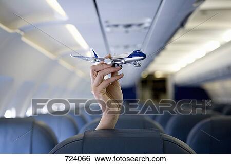 A hand holding a toy airplane above an airplane seat View Large Photo Image Stock Photograph - A hand holding a toy airplane above an airplane seat. Fotosearch