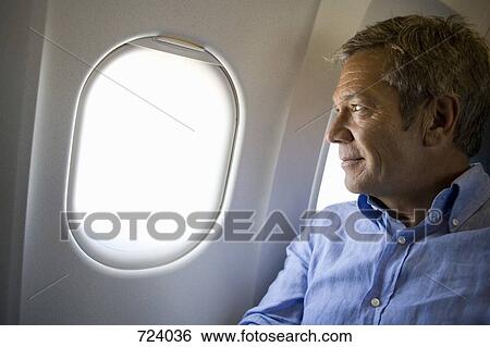 A male passenger on a plane looking through window View Large Photo Image Stock Photograph - A male passenger on a plane looking through window. Fotosearch