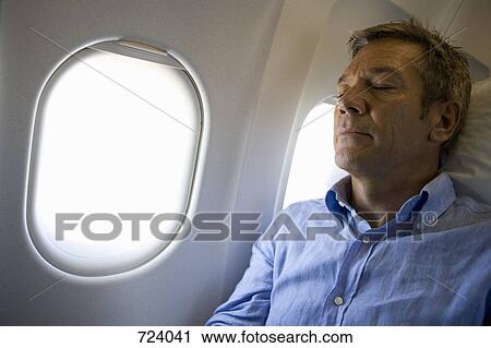 Stock Image - A male passenger sleeping on a plane. Fotosearch
