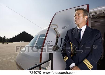A pilot standing in front of the doorway of a plane View Large Photo Image Stock Image - A pilot standing in front of the doorway of a plane. Fotosearch