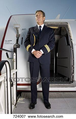 Stock Photo - A pilot standing in front of the doorway of a plane. Fotosearch