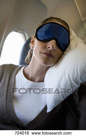A woman wearing a sleep mask sleeping on a plane View Large Photo Image Stock Photograph - A woman wearing a sleep mask sleeping on a plane. Fotosearch
