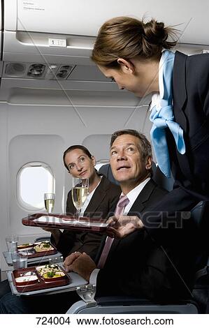 Business people on a plane being served meals and champagne View Large Photo Image Picture - Business people on a plane being served meals and champagne. Fotosearch
