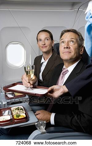 Business people on a plane being served meals and champagne View Large Photo Image Stock Photo - Business people on a plane being served meals and champagne. Fotosearch