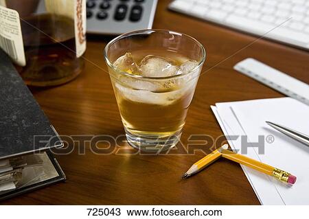 A glass of whiskey and ice on an office desk View Large Photo Image Stock Image - A glass of whiskey and ice on an office desk. Fotosearch