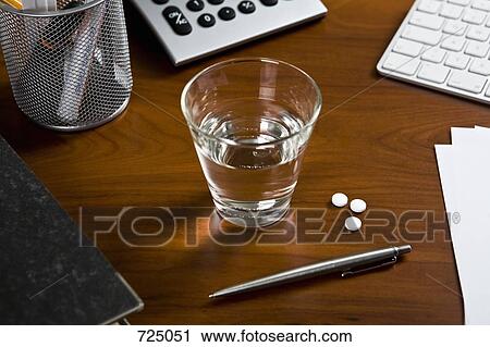 An office desk with a pen and a glass of water with three aspirin next to it View Large Photo Image Stock Image - An office desk with a pen and a glass of water with three aspirin next to it. Fotosearch