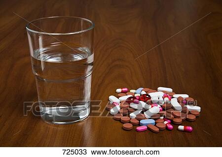 Pills next to a glass of water View Large Photo Image Stock Image - Pills next to a glass of water. Fotosearch