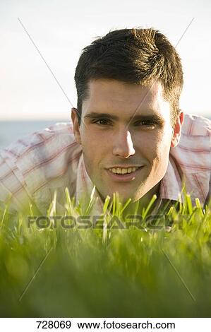 A man lying in grass, heads and shoulders, surface level View Large Photo Image Stock Photo - A man lying in grass, heads and shoulders, surface level. Fotosearch