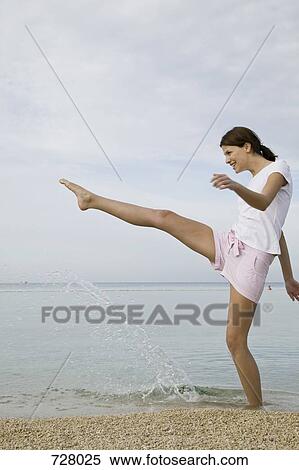 Stock Photography - A woman kicking water up with her foot. Fotosearch