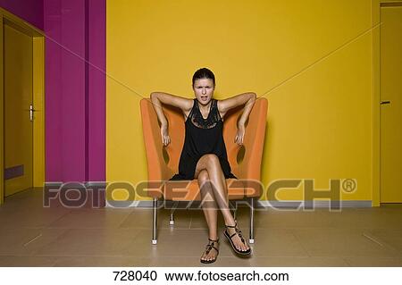 A woman sitting in a designer chair looking shocked View Large Photo Image Stock Image - A woman sitting in a designer chair looking shocked. Fotosearch