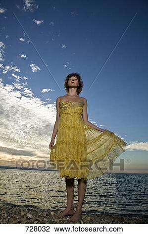 A woman wearing a dress standing by the sea View Large Photo Image Stock Image - A woman wearing a dress standing by the sea. Fotosearch