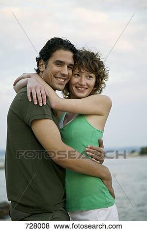 A young couple embracing by the sea View Large Photo Image Stock Photo - A young couple embracing by the sea. Fotosearch