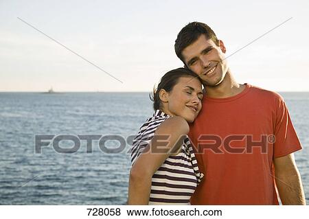 Stock Photo - A young couple relaxing by the sea. Fotosearch