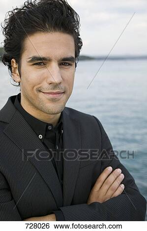Stock Photograph - A young man with his arms crossed, portrait. Fotosearch