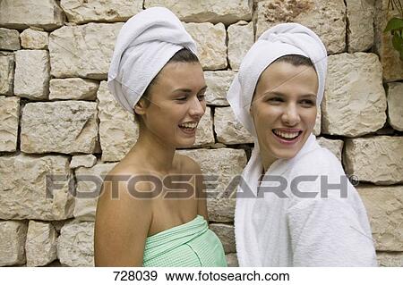 One woman wrapped in a towel laughing with another woman in a bathrobe View Large Photo Image Stock Photo - One woman wrapped in a towel laughing with another woman in a bathrobe. Fotosearch