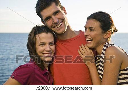 Stock Photo - Three friends sharing a laugh by the sea. Fotosearch