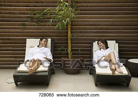 Two women lying in lounge chairs View Large Photo Image Stock Photography - Two women lying in lounge chairs. Fotosearch