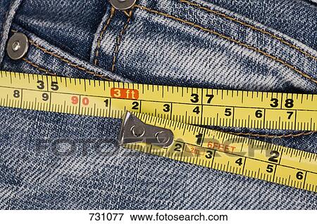 A tape measure around jeans, extreme close-up View Large Photo Image Stock Photo - A tape measure around jeans, extreme close-up. Fotosearch