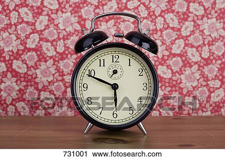 An old fashioned alarm clock in front of floral patterned wallpaper View Large Photo Image Stock Image - An old fashioned alarm clock in front of floral patterned wallpaper. Fotosearch