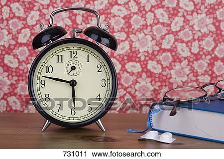 An old-fashioned alarm clock next to a book, eyeglasses and a blister pack View Large Photo Image Stock Image - An old-fashioned alarm clock next to a book, eyeglasses and a blister pack. Fotosearch
