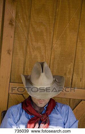 A cowboy resting with his hat tilted over his face View Large Photo Image Stock Photo - A cowboy resting with his hat tilted over his face. Fotosearch