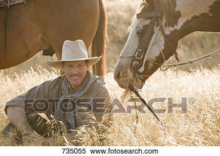 A cowboy sitting in long grass with two horses View Large Photo Image Stock Photography - A cowboy sitting in long grass with two horses. Fotosearch