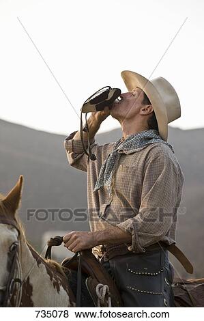 A cowboy sitting on a horse and drinking from a hip flask View Large Photo Image Stock Photo - A cowboy sitting on a horse and drinking from a hip flask. Fotosearch