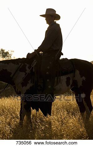 Stock Photograph - A cowboy sitting on a horse at dusk. Fotosearch