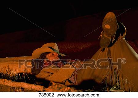 A cowboy sleeping next to a campfire View Large Photo Image Stock Image - A cowboy sleeping next to a campfire. Fotosearch