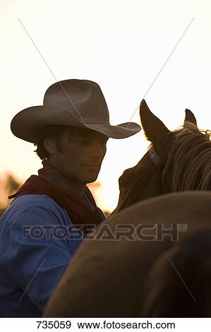 A cowboy standing next to his horse View Large Photo Image Stock Photo - A cowboy standing next to his horse. Fotosearch