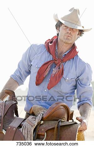 A Cowboy Tragen A Pferd Pferdesattel Stock Fotograf Fotosearch