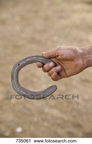 Stock Image - A hand holding a horseshoe. Fotosearch