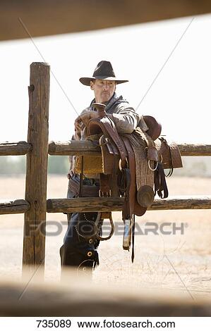 A rancher leaning against a saddle on a fence View Large Photo Image Stock Photo - A rancher leaning against a saddle on a fence. Fotosearch