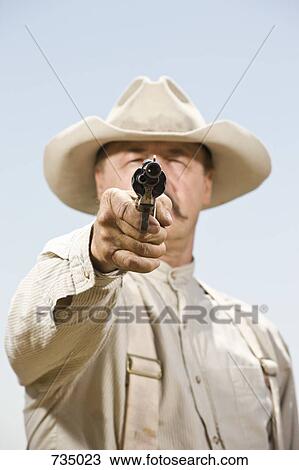 Stock Image - Close up of a cowboy aiming his gun. Fotosearch