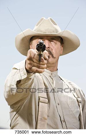 Portrait of a cowboy aiming his gun ready to shoot View Large Photo Image Stock Image - Portrait of a cowboy aiming his gun ready to shoot. Fotosearch