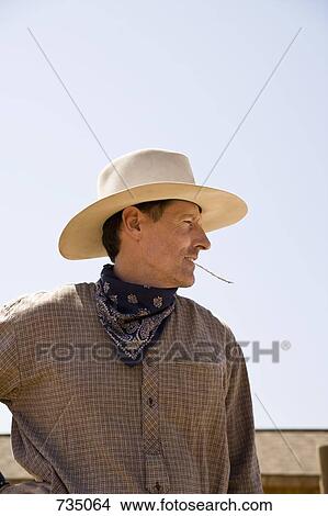 Picture - Profile of a cowboy chewing on a piece of straw. Fotosearch
