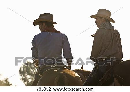 Rear view of two cowboys riding horses View Large Photo Image Stock Image - Rear view of two cowboys riding horses. Fotosearch