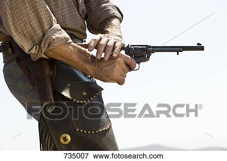 Side view of a cowboy shooting a gun View Large Photo Image Stock Photo - Side view of a cowboy shooting a gun. Fotosearch