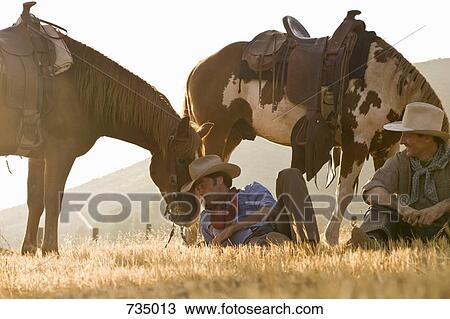 Two cowboys resting with their horses View Large Photo Image Stock Image - Two cowboys resting with their horses. Fotosearch