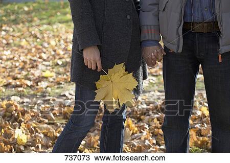 Stock Image - A man and woman holding hands in autumn, outdoors. Fotosearch