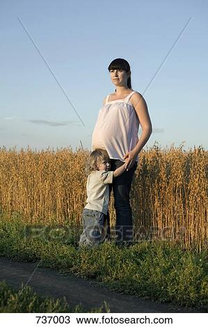 A pregnant woman and her young boy standing near a wheat field View Large Photo Image Stock Image - A pregnant woman and her young boy standing near a wheat field. Fotosearch