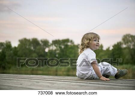 A smiling boy sitting on a jetty View Large Photo Image Stock Photo - A smiling boy sitting on a jetty. Fotosearch