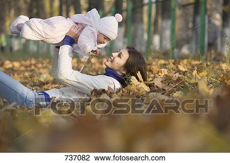 A teenage girl lying down lifting a baby up View Large Photo Image Stock Image - A teenage girl lying down lifting a baby up. Fotosearch