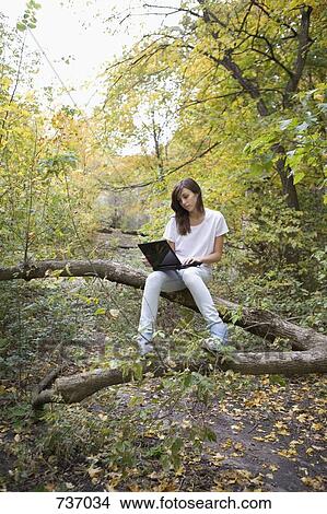 A teenage girl using a laptop sitting in nature View Large Photo Image Picture - A teenage girl using a laptop sitting in nature. Fotosearch