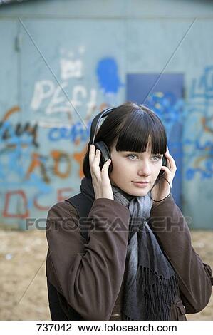 A teenage girl wearing headphones, outdoors View Large Photo Image Stock Image - A teenage girl wearing headphones, outdoors. Fotosearch