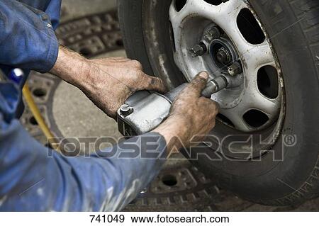 A car mechanic unscrewing a wheel View Large Photo Image Stock Photo - A car mechanic unscrewing a wheel. Fotosearch